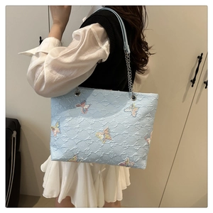 Detail of light blue tote bag with butterfly embroidery and silver chain strap