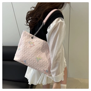 Detail of pink tote bag with 3D geometric texture and colorful butterfly embroidery