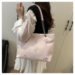 Detail of pink tote bag with 3D texture, butterfly embroidery and chain strap
