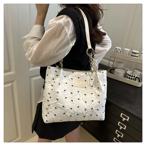 Détail du sac cabas blanc avec texture florale 3D et nœuds papillons noirs