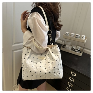 Detail of white tote bag with black bow embroidery and gold metal ring hardware