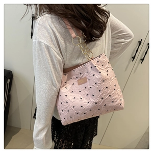 Detail of pink bow-print tote bag with embossed texture and metal chain strap