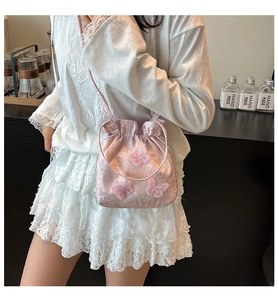 Detailed view of pink drawstring bucket bag featuring 3D mesh butterfly appliques