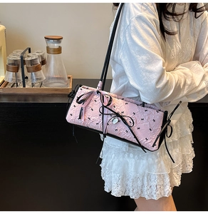 Dettaglio della borsa baguette in garza rosa con fiocchi neri indossata dalla modella