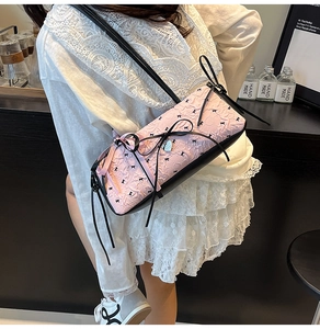 Dettaglio della borsa a spalla jacquard rosa con fiocchi neri e ciondolo a cuore in metallo