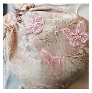 Detail of pink embroidered bucket bag with lace butterfly appliques and jacquard texture