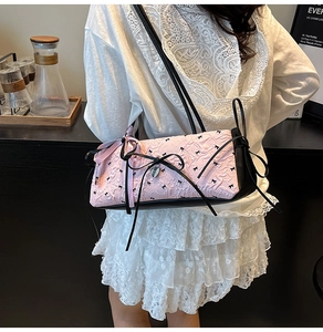 Dettaglio della borsa a secchiello rosa con fiocco e ciondolo a cuore su una modella
