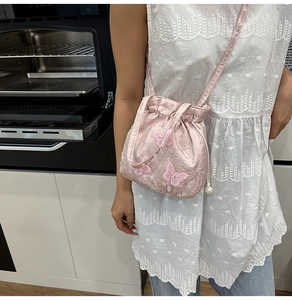 Detail of pink satin bucket bag with 3D butterfly embroidery and pearl drawstring strap