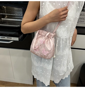 Detailed embroidery of pink butterfly patterns and pearl drawstring on a bucket bag