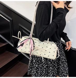 Dettaglio borsa baguette bianca in seersucker con fiocchi neri e nastri colorati appesi