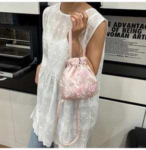 Detail of pink embroidered silk bucket bag with delicate 3D butterfly and pearl charm