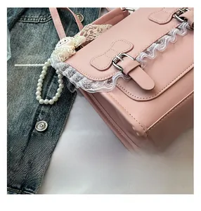 Gros plan du sac en similicuir rose avec dentelle, boucle nœud et pendentif mouton blanc