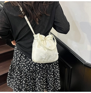 Detail of white embroidery bucket bag with butterfly lace and drawstring on model