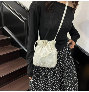 Detail of white jacquard bucket bag with floral butterfly texture and drawstring closure