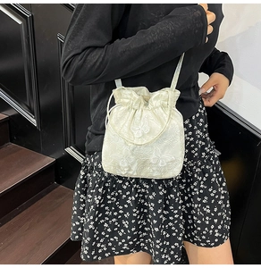 Detail of white drawstring bucket bag with exquisite butterfly embroidery and long strap