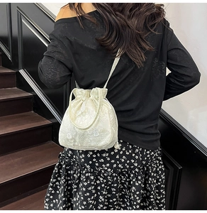 Detailed texture of white floral lace embroidery on a stylish drawstring bucket bag