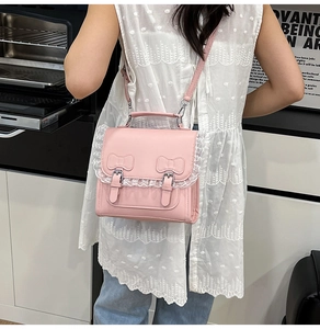 Détail latéral du sac rose en similicuir avec bordure en dentelle et nœud élégant