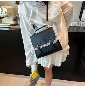 Détail du sac bandoulière Lolita noir avec bordure en dentelle blanche et nœuds en cuir