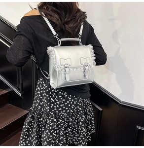 Détail du sac à dos en PU argenté brillant avec bordure en dentelle blanche et boucles à nœud