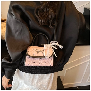 Detail of pink bow handbag featuring lace pearl charm and silver butterfly clasp