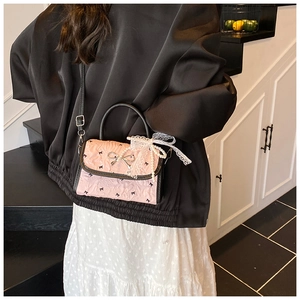 Pink bow handbag with pearl lace details shown being worn on a shoulder in a lifestyle shot