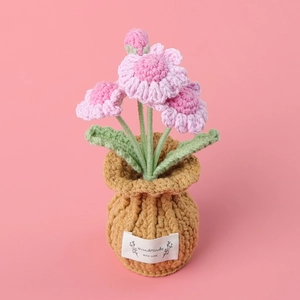 Close-up of handmade crochet pink flower pot with Handmade With Love label on pink base