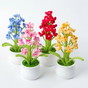 Detail of four handmade crochet flower pots with faux pearl accents in white ceramic pots