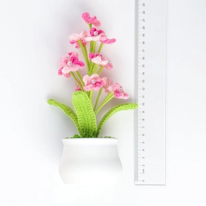 Handmade crochet pink flower pot with pearls and green leaves on white background