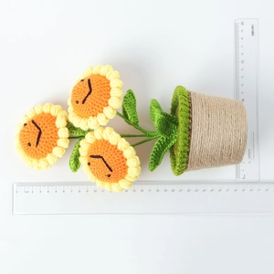 Detail view of handmade crochet sunflower plant with measuring ruler for scale