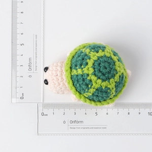 Detailed size display of a handmade crochet pink turtle doll with a green shell