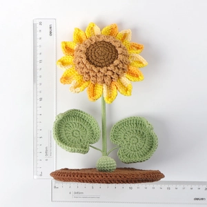 Handmade crochet sunflower phone holder stand with green stem on brown woven base