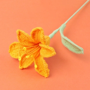 Macro detail of handmade crochet orange lily flower with yellow stamen and fine knit texture