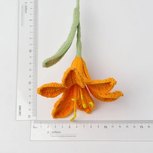 Detailed macro view of handmade crochet orange lily with dimensions on ruler