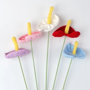 Detail of five handmade crochet anthurium flowers in vibrant colors on a white background