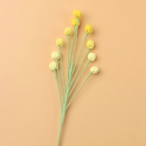 Close-up of handmade crochet snowberry bouquet with soft yellow knit buds and green stems