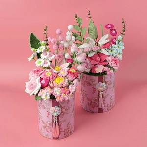 Detalle de ramo de flores de ganchillo hecho a mano en caja floral con borlas rosadas