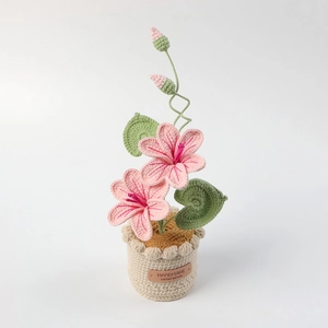 Handmade crochet pink flower potted plant with green leaves and a beige knit pot