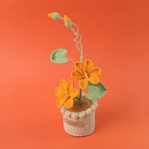 Handmade crochet orange blossom potted plant with green leaves and a handmade label