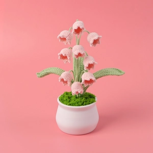 Détail de muguet fait main au crochet rose dans un petit pot en céramique blanche