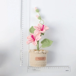 Detailed view of handmade crocheted pink floral plant with scale ruler for size reference