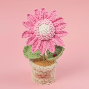 Macro detail of handmade crochet pink sunflower in beige pot with a tiny red ladybug