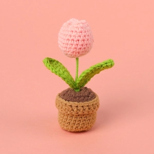 Close-up of pink handmade crochet tulip in a pot with soft yarn texture details