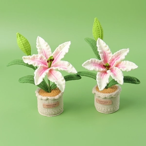 Handmade crochet lily flower potted plants with pink petals and green leaves on desk