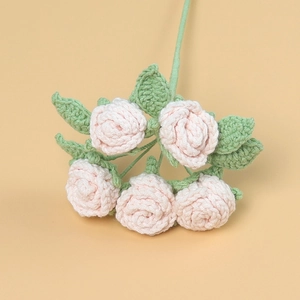Détail de cinq roses roses crochetées à la main avec texture tricotée et feuilles vertes