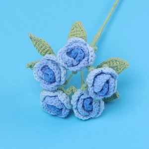 Bouquet de cinq roses bleues crochetées à la main avec feuilles vertes sur fond bleu