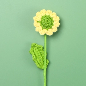 Detailed close-up of handmade crochet sunflower with yellow petals and green core texture