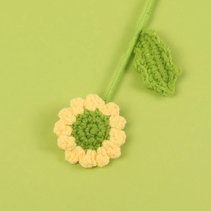 Handmade crochet sunflower with yellow petals and green stem on a matching background