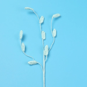 Handmade crochet grass stem with mint green leaves on a solid blue background