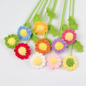 Flat lay of colorful handmade crochet daisies with detailed knit texture on white background