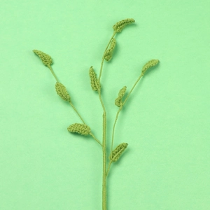 Close-up of handmade crochet green leaf sprig with detailed knitted texture on paper